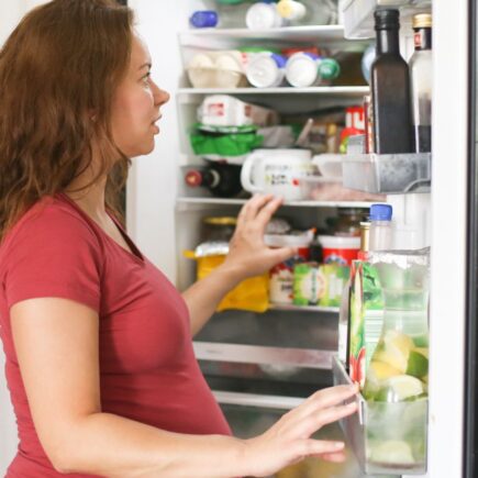 a lady taking out old food from the refrigerator