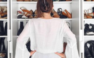 a lady standing in her shoe closet confused