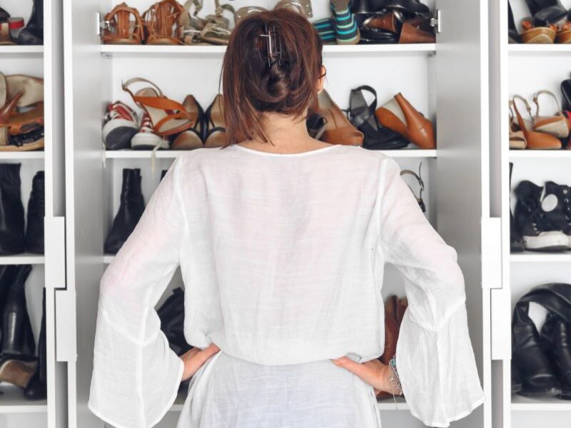 a lady standing in her shoe closet confused