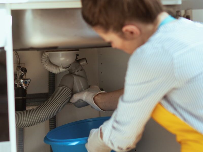 a lady cleaning under the kitchen sink