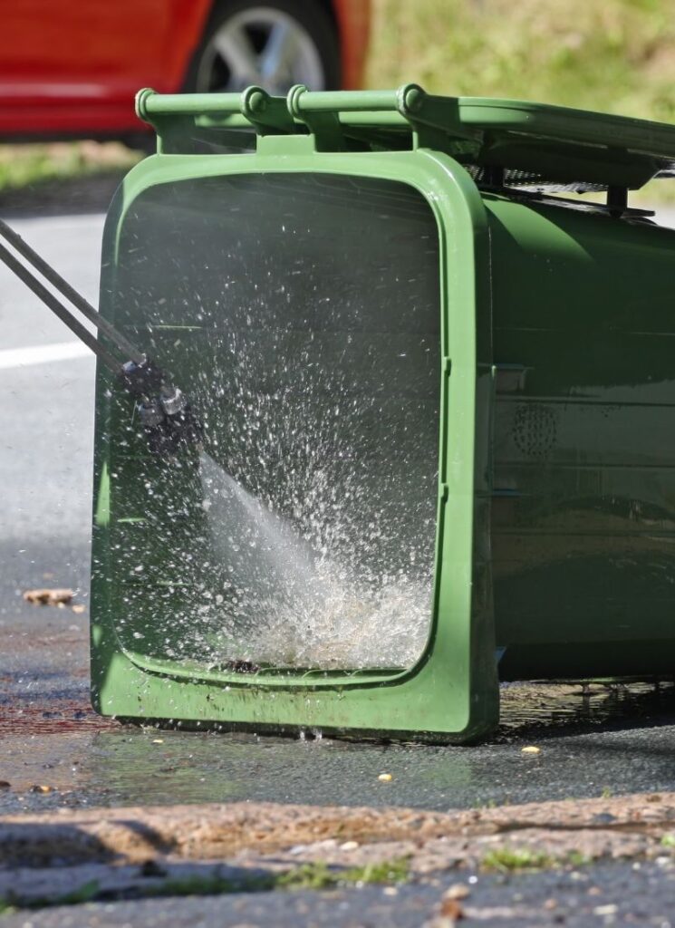 a lady washing her trash bin
