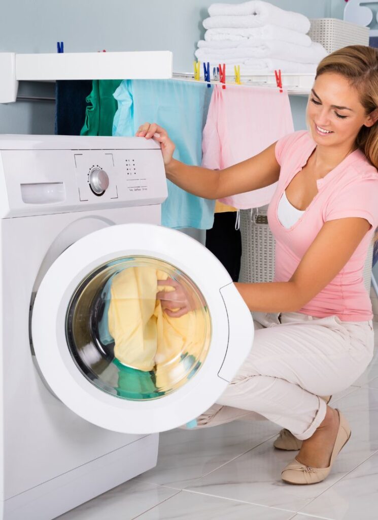 a lady putting away dirty clothes in the washing machine