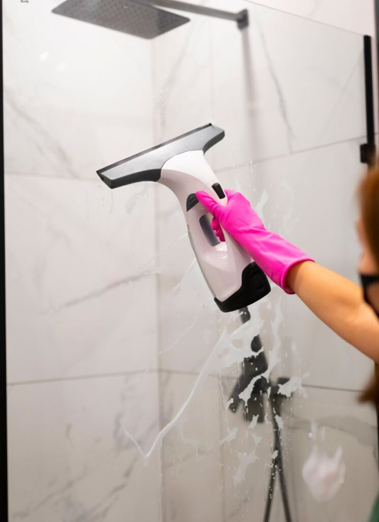 a lady cleaning the shower glass